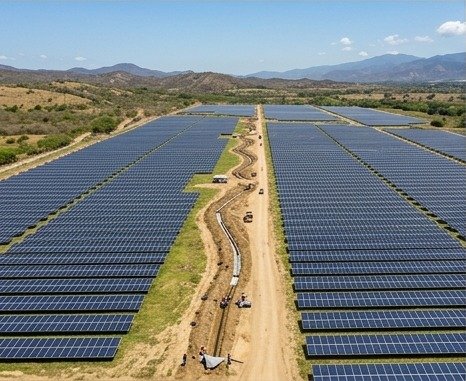 Panorámica aérea de un parque solar en construcción, con montañas de fondo